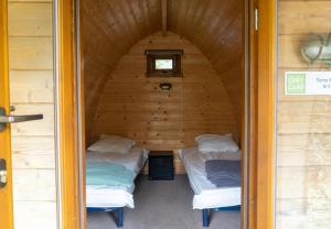 dwa łóżka w drewnianym domku z oknem w obiekcie Camping Onlycamp La Potinière w mieście Écueillé