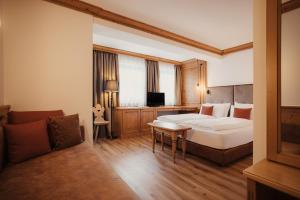Habitación de hotel con cama y sofá en Diana Dolomites Living & Taste, en La Villa