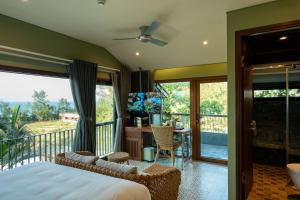 a bedroom with a balcony with a bed and a desk at CHiEM HoiAn - The Beachside Boutique Hotel & Villa in Hoi An