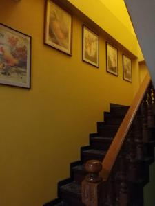 eine Treppe mit Gemälden an einer gelben Wand in der Unterkunft นอนในสวน รีสอร์ท in Bangkok