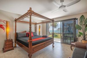 a bedroom with a canopy bed with a view of the ocean at Baligara Absolute Oceanfront Guest Suite in Bargara