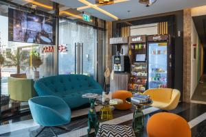 izzzilife Mint في دبي: يوجد متجر به أريكة زرقاء وكراسي برتقالية