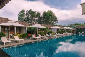 a pool at a resort with chairs and umbrellas at Pilgrimage Village Boutique Resort & Spa in Hue +35 photos