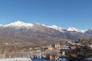 a town with snow covered mountains in the background at Les Chardons - Apt duplex vue montagne in Saint-Léger-les-Mélèzes