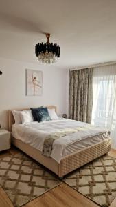 a bedroom with a large bed and a chandelier at Modern Apartament with a view in Râmnicu Vâlcea