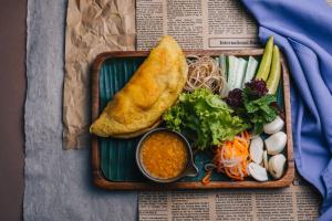 a plate of food with a piece of bread and vegetables at Pilgrimage Village Boutique Resort & Spa in Hue