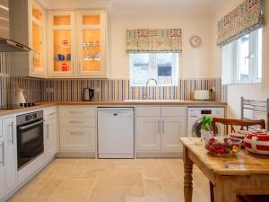 a kitchen with white cabinets and a wooden table at Sundown Lodge in Chipping Campden
