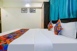1 dormitorio con 1 cama blanca grande con almohadas coloridas en FabExpress Bindra Elite en Bombay