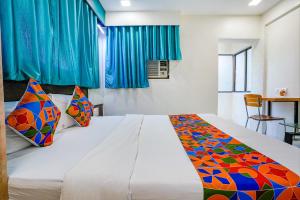 a bedroom with a large white bed with colorful pillows at FabExpress Bindra Elite in Mumbai