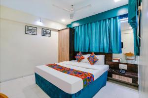 a bedroom with a bed and a blue curtain at FabExpress Bindra Elite in Mumbai