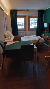 Cette chambre comprend deux lits, une table et des chaises. dans l'établissement Dea Diana, à Passo del Tonale