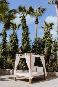 a white canopy bed with palm trees in the background at Sa Talaia Blanca in Muro