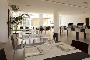 uma sala de jantar com mesas brancas e cadeiras com copos em Inn Naples Airport em Gricignano dʼAversa