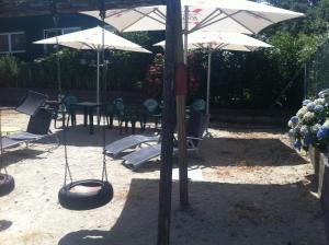 a patio with swings and tables and umbrellas at Hostal Meson do Loyo in Portomarin