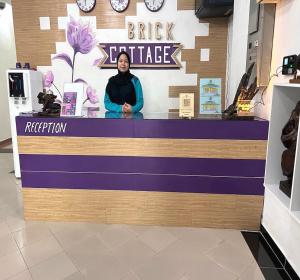 a woman standing behind a counter in a store at OYO 90907 Brick Cottage Homes in Kuah