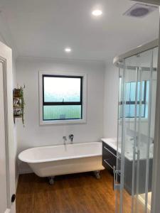 baño con bañera blanca y ventana en Kereru Cottage en Kaikoura