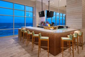una cocina con una barra con sillas y ventanas en SpringHill Suites by Marriott Panama City Beach Beachfront en Panama City Beach