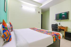 a bedroom with a white bed and a tv at Aruba Suites in Noida