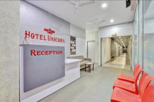 a hotel lobby with a hotel entrance and red chairs at Hotel Unicorn, Surat in Surat