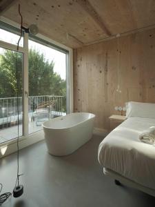 a bedroom with a tub and a bed and a window at Hotel Amiuka in O Pedrouzo