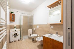 bagno con lavandino e servizi igienici e lavatrice. di Asiago Centro - Comodissimo Appartamento al Piano Terra ad Asiago