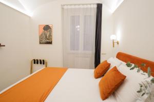 a bedroom with a large white bed with orange pillows at Charm&Bella GuestHouse in Rome