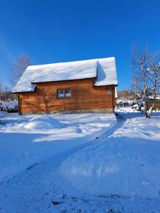 a log cabin with a snow covered roof in a yard at Wrzos Chata w Beskidach in Kamesznica
