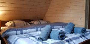 a bed in a wooden room with blue pillows on it at Wrzos Chata w Beskidach in Kamesznica