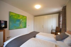 1 dormitorio con 1 cama y una pintura en la pared en Ferienhaus Auszeit en Borkum