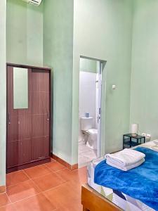 a bedroom with a bed and a bathroom with a toilet at Telu.Telu Solo in Solo