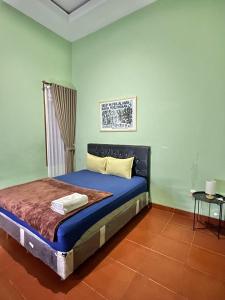 a bedroom with a bed with blue sheets and a window at Telu.Telu Solo in Solo