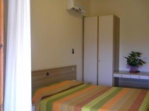 a bedroom with a bed and a cabinet and a plant at Hotel Rosa Del Tirreno in Quercianella