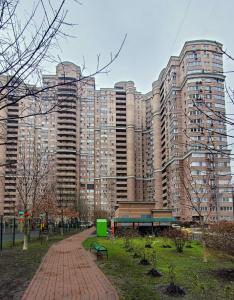 un parque con un banco frente a un gran edificio en Golosievo residence 60m2, en Kiev