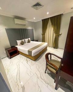 um quarto de hotel com uma cama e uma cadeira em Continental Suite farwaniya em Kuwait