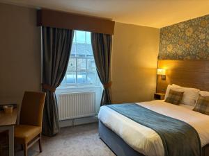 a hotel room with a bed and a desk and a window at Snooty Fox in Kirkby Lonsdale
