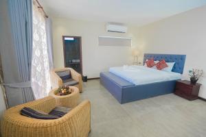 1 dormitorio con 1 cama y 2 sillas de mimbre en Private Villa, en Phumĭ Kântrák