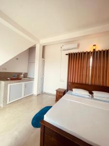 a bedroom with a large bed and a kitchen at Devo's place in Galle