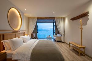 sypialnia z dużym łóżkiem i dużym oknem w obiekcie Dali Beauty Seaview B&B w mieście Dali