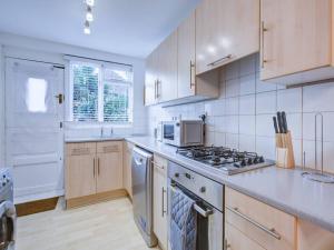 uma cozinha com armários brancos e um forno com placa de fogão em Pass the Keys Charming 2 Bedroom House Good Transport and Parking em Londres