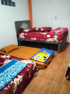 een kamer met 2 bedden op een houten vloer bij KHAIRI HOMESTAY in Bukittinggi