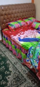 een bed met een kleurrijke deken en kussens erop bij KHAIRI HOMESTAY in Bukittinggi