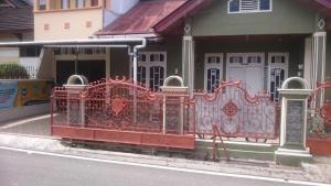 een rood hek aan de zijkant van een gebouw bij KHAIRI HOMESTAY in Bukittinggi