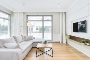 a white living room with a white couch and a tv at Elite Apartments Rezydencja Marina in Gdańsk