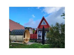 uma pequena casa vermelha com um barril grande à frente em Villa Königsdorf am See em Waldkirchen