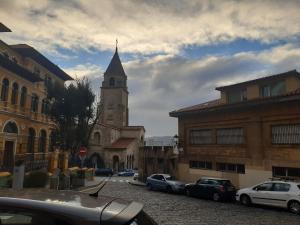 a church with a clock tower in a city at Apartamentos Bahia San Lorenzo in Gijón