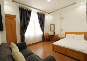 1 dormitorio con cama, sofá y escritorio en Maxim Hotel en Da Lat