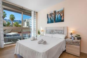 a bedroom with a white bed with a large window at Apartamento Melior 2C - PlusHolidays in Calpe