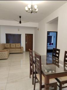 a dining room and living room with a glass table and chairs at Himasailam Resort in Vagamon