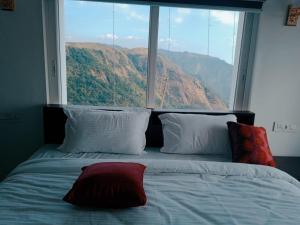 a bed with a view of a mountain from a window at Himasailam Resort in Vagamon