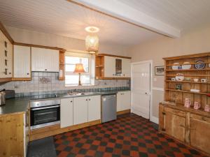 uma cozinha com armários brancos e um piso xadrez em Alcorns Farmhouse em Letterkenny